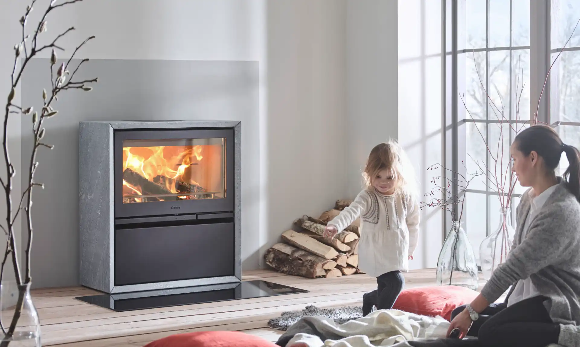Maman et sa fille devant un poêle à bois en feu
