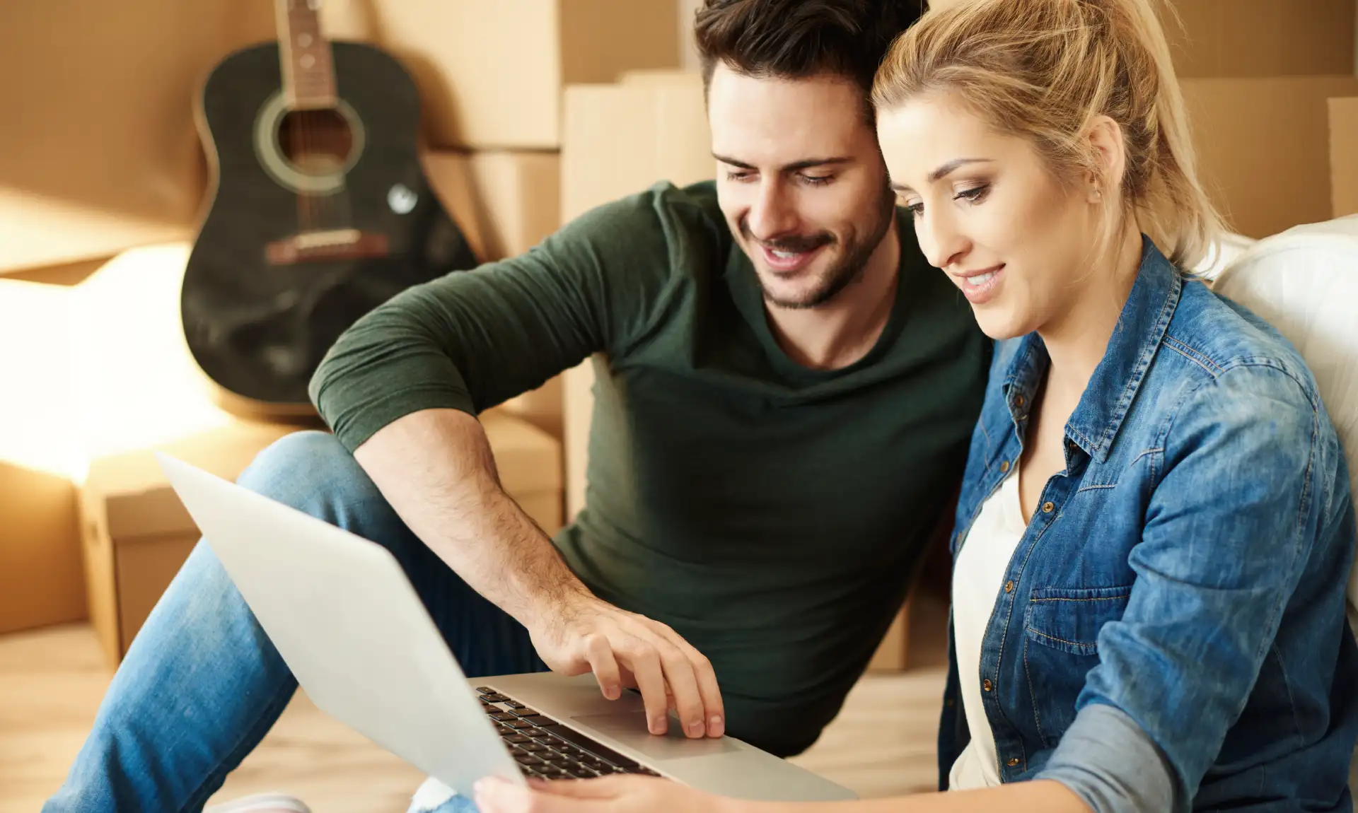 Couple regardant un ordinateur en plein déménagement